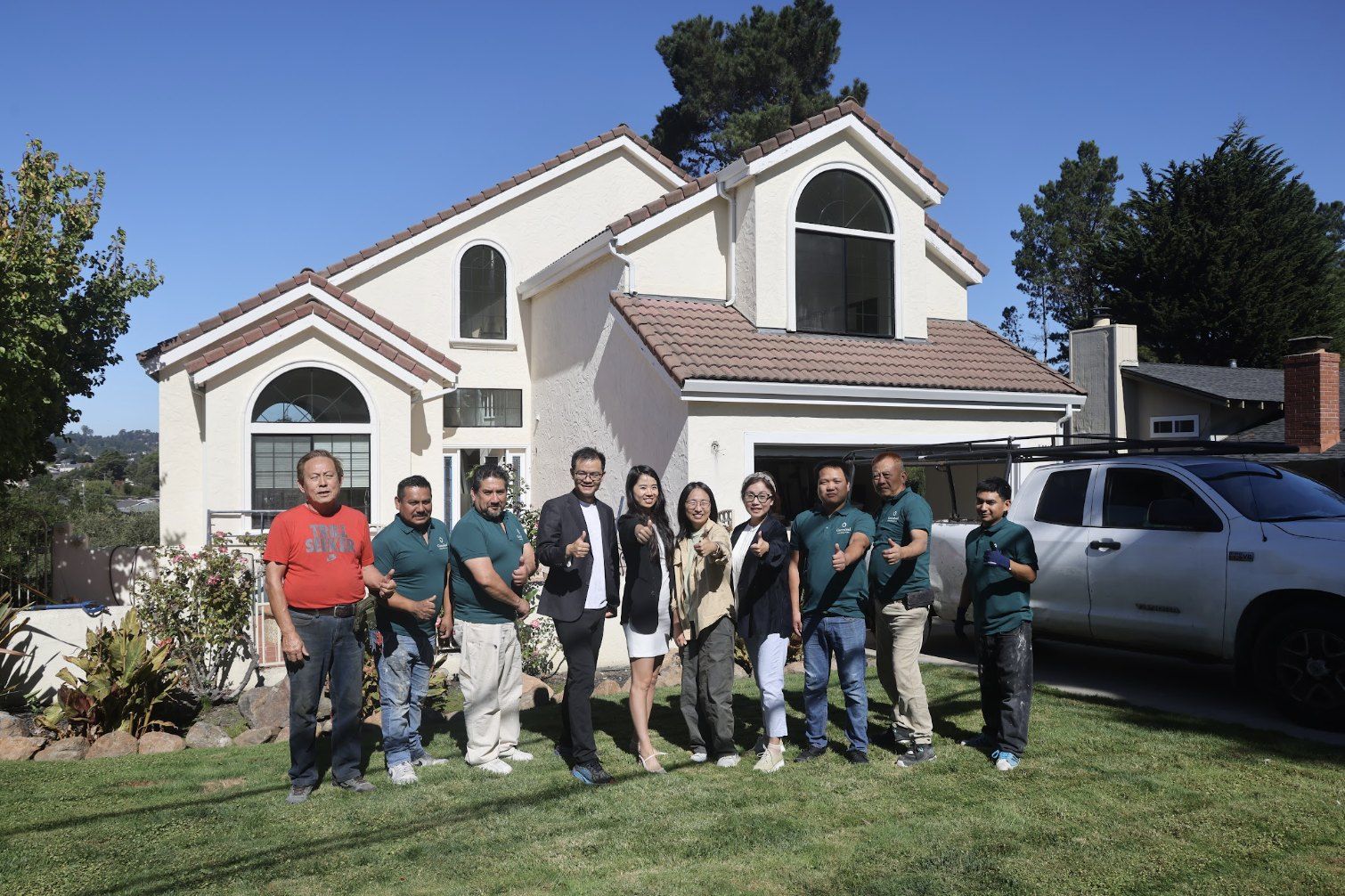 The Greenland team and construction crew giving thumbs up in front of a two-story home