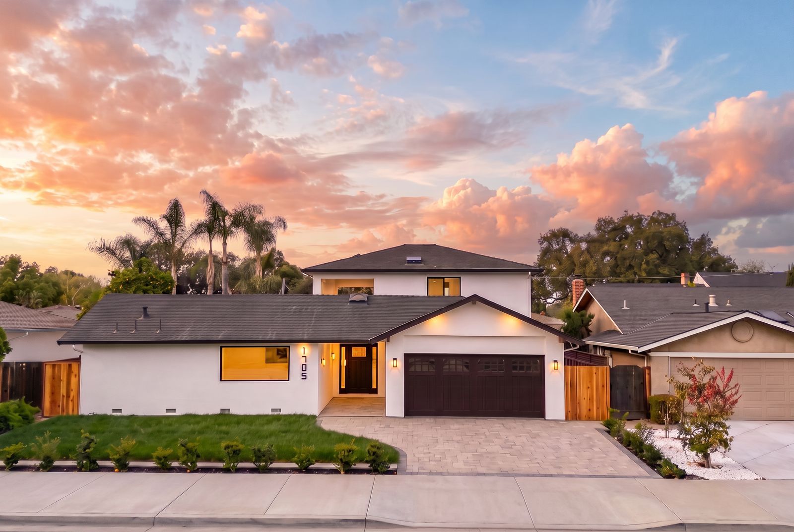 Remodeled two-story white home with a paver driveway at sunset