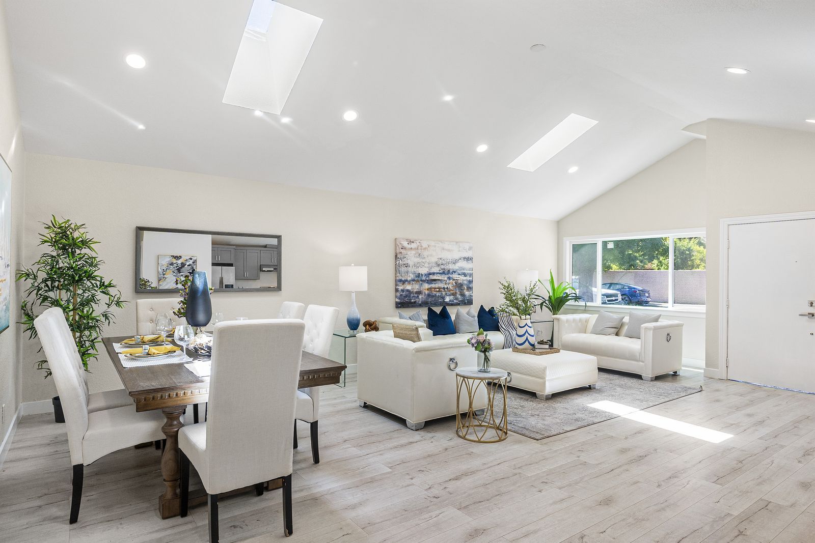 Bright living and dining room under a vaulted ceiling with skylights